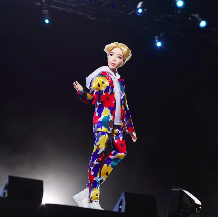 Dalam action figure ini, Jin BTS tampil colorfull dengan baju dan celana bunga-bunga yang dipadukan dengan sepatu berwana putih.