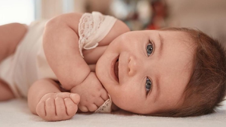 nama bayi cute baby girl having fun and laughing, lying on side. lifestyle shot.