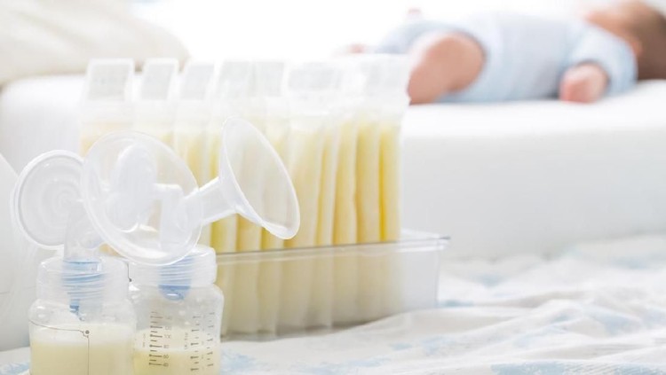 Breast milk frozen in storage bag and baby lying on background
