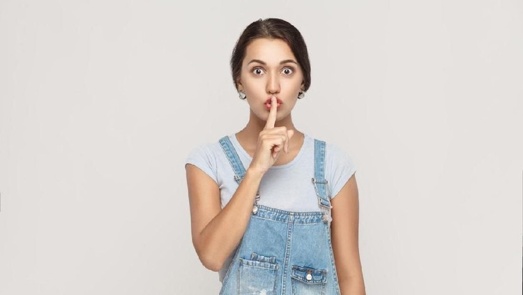Shh sign. Beautiful indian woman looking at camera with silent sign. Studio shot, on gray background.
