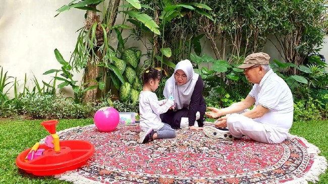 Ditemani istrinya Wury Estu Handayani, Ma'ruf yang mengenakan kaus, topi, dan sepatu olahraga bermain bola bersama cucu.