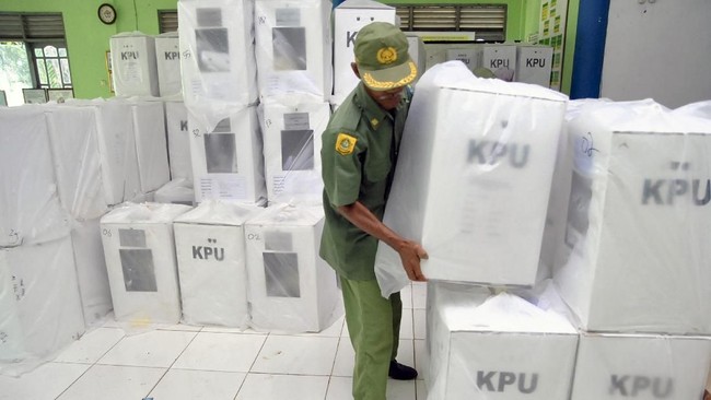 Petugas Hansip mengangkat kotak surat suara yang dibungkus plastik saat distribusi logistik Pemilu 2019 untuk Desa Leuwinutug di aula serbaguna PGRI, Ciseeng, Kabupaten Bogor, Jawa Barat, Selasa (16/4/2019). KPU Kabupaten Bogor mengganti sebanyak 682 kotak surat suara Pemilu 2019 yang rusak akibat banjir pada Minggu (14/4/2019) malam dengan menggunakan kotak surat suara bekas Pemilihan Kepala Daerah (Pilkada) Jawa Barat pada tahun 2018. ANTARA FOTO/Arif Firmansyah/foc.