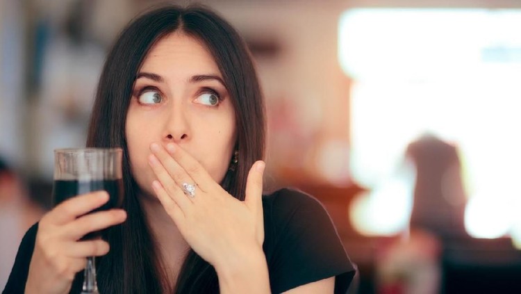 Woman covering her moth after drinking cola
