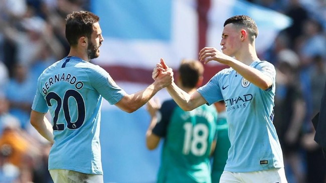 Gelandang Manchester City, Bernardo Silva, menyerahkan gelar Man of the Match yang didapat kepada rekan setimnya, Phil Foden.