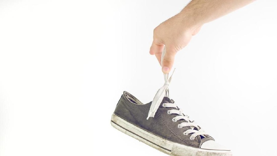 Woman Holding Dirty Stinky Shoes Covering Her Nose
