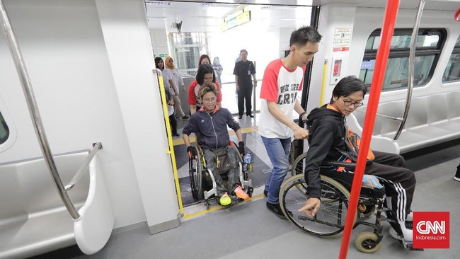 Petugas membantu seorang penyandang disabilitas naik ke kereta LRT di Stasiun LRT Veldrome, Jakarta, Sabtu (27/4). kegiatan yang diikuti Jakarta Barrier Free Tourism (JBFT) tersebut untuk mengenalkan lebih dekat LRT. (CNN Indonesia/Adhi Wicaksono)