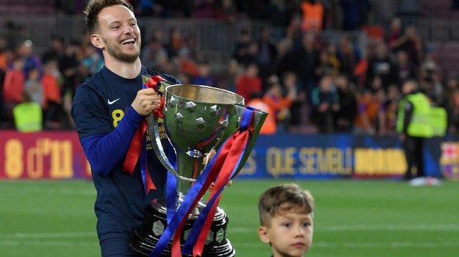 Barcelona's Croatian midfielder Ivan Rakitic holds the trophy as he celebrates becoming La Liga champions after winning the Spanish League football match between FC Barcelona and Levante UD at the Camp Nou stadium in Barcelona on April 27, 2019. - Lionel Messi clinched an eighth La Liga title for Barcelona in 11 seasons today as he scored the only goal in a 1-0 win over Levante. It is the Catalan club's 26th league title -- second in Spain to Real Madrid's record of 33. (Photo by LLUIS GENE / AFP)