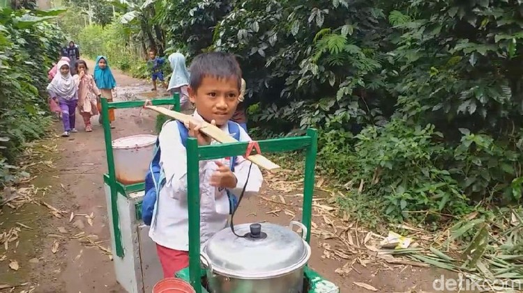 Sambil mengenakan seragam dan tas sekolah, Erwin Utama memikul gerobak bakso tahu berkeliling kampung.