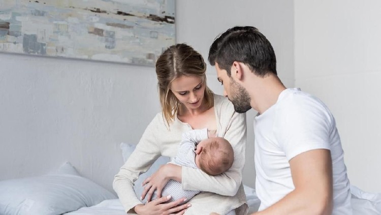 young husband looking how mother feeding little baby