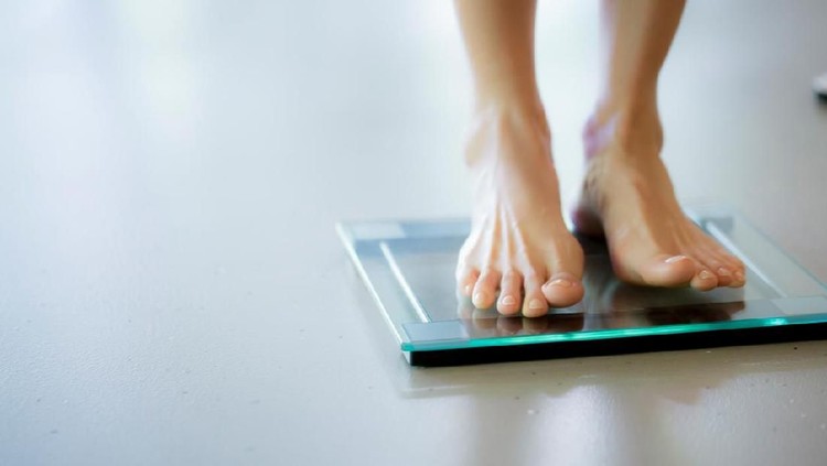 Female is dieting and checking her weight on the scale, selective focus