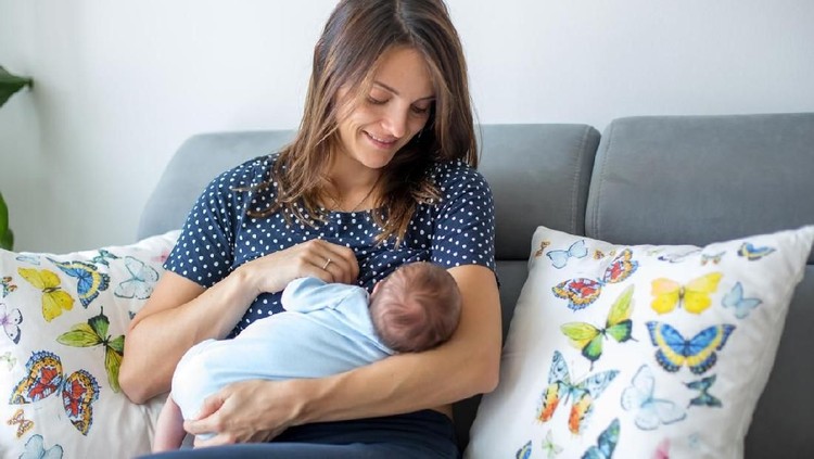 Young mother breastfeeding  her newborn baby boy at home