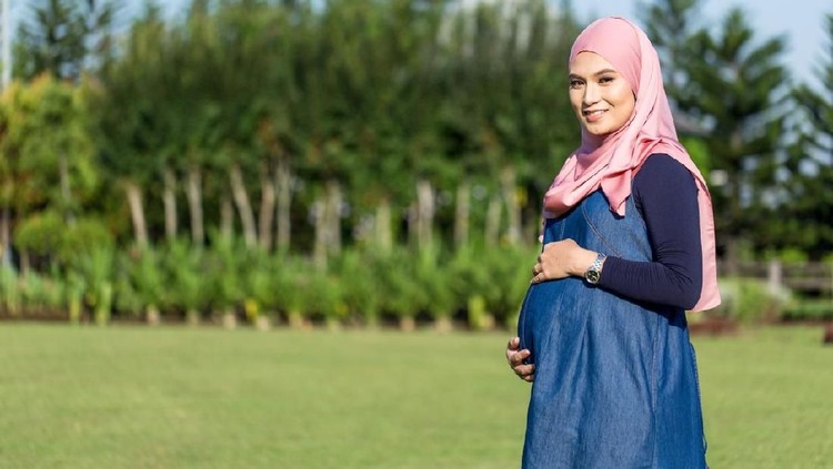 ibu hamil Young pregnant women with blue dress standing and holding belly
