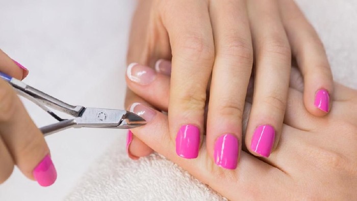 Nail technician clipping customers nails at the nail salon