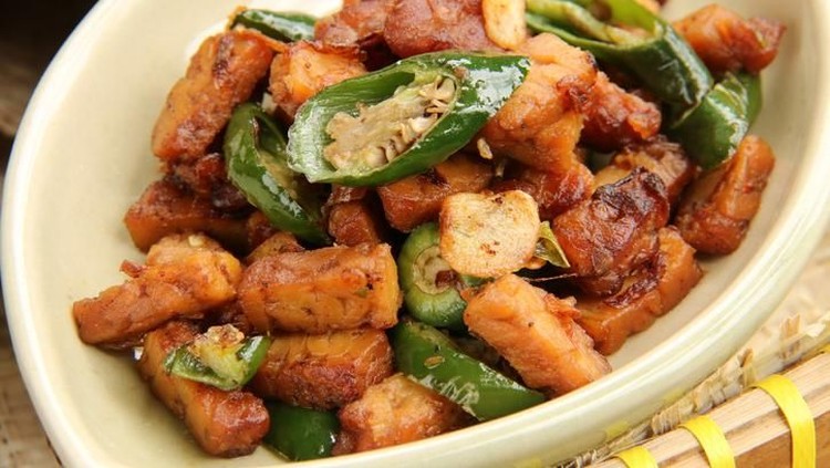 Tempeh, fermented soybean cake, sautÃ©ed with green chili and seasoned with Indonesian sweet soy sauce. Popular as side dish for many Indonesian rice dishes such as Nasi Uduk Betawi. The tempeh is plated on an oval ceramic plate; which then placed on traditional bamboo tray.