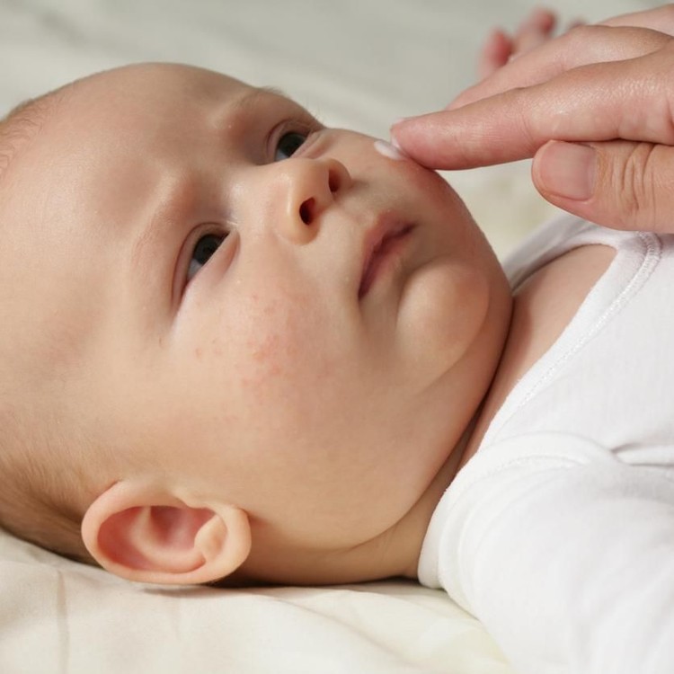 Female hand applying the cream on baby's face