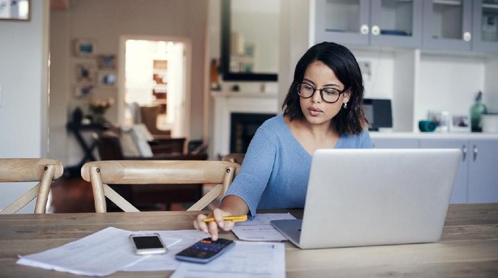 Shot of a young couple using a laptop and going through paperwork at home