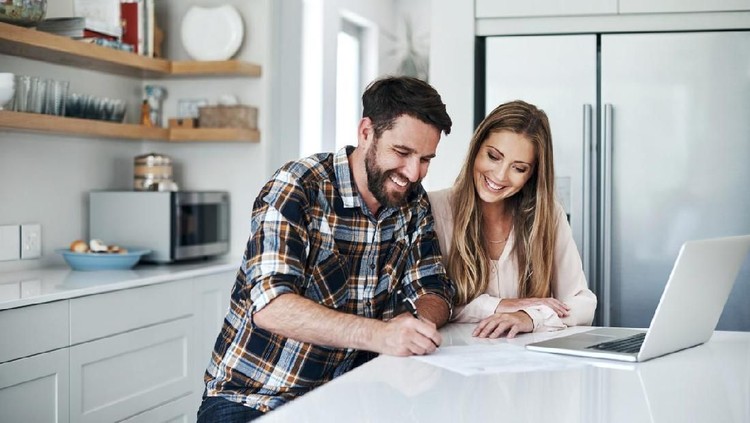 Shot of a young couple using a laptop and going through paperwork at home
