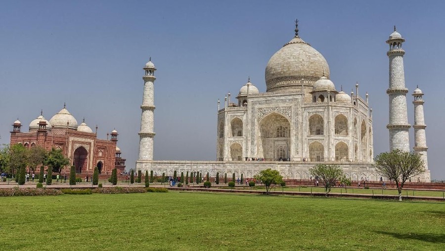 Agra, India - September 21, 2015: Muslim tourists posing for a photograph in one of the two grand red sandstone buildings that mirror each other, and face the sides of the tomb of Taj Mahal Agra India This one is a mosque