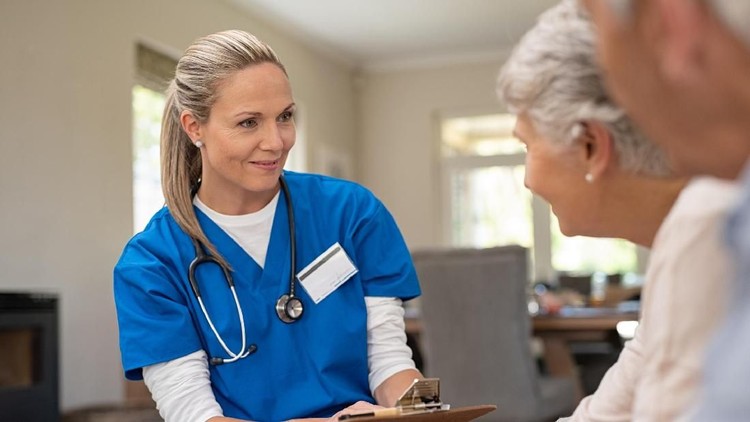 Happy nurse talking to senior patients in private clinic. Senior couple consulting health and medical report with doctor at home. Old man and elderly woman visiting the nurse with clipboard and health issues.