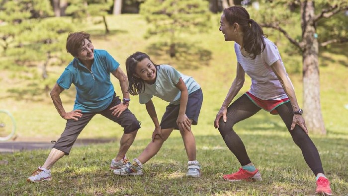 Grandmother with her friend and granddaughter doing exercises in Yoyogi park on a sunny day.