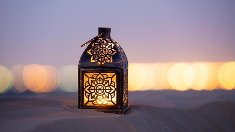 Traditional ornamental arabic lantern with a burning candle in desert after sunset during blue hour. Festivel greeting card for Ramadan Kareem and Ramadan Mubarak. Dubai, UAE.