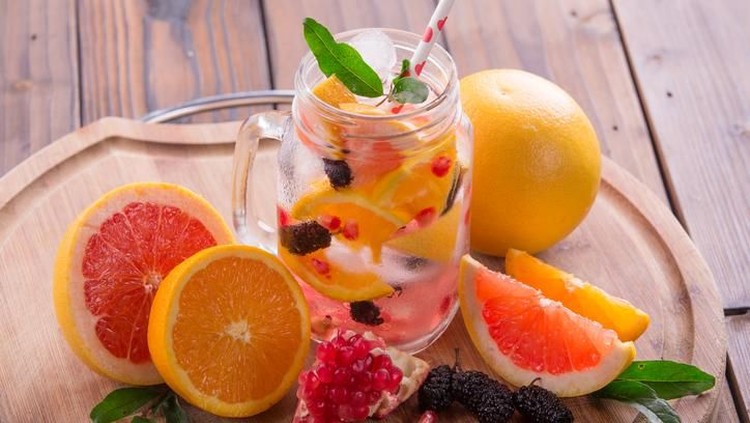 Refreshing sangria / punch with orange, pomegranate seeds, blackberry, and grapefruit on brown rustic wooden background