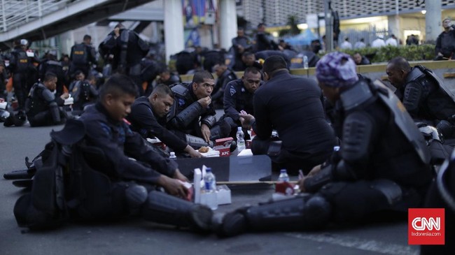 Polisi yang bertugas menghadapi massa perusuh tetap melaksanakan ibadah puasa dan rela bersantap sahur di tengah jalan demi keamanan.