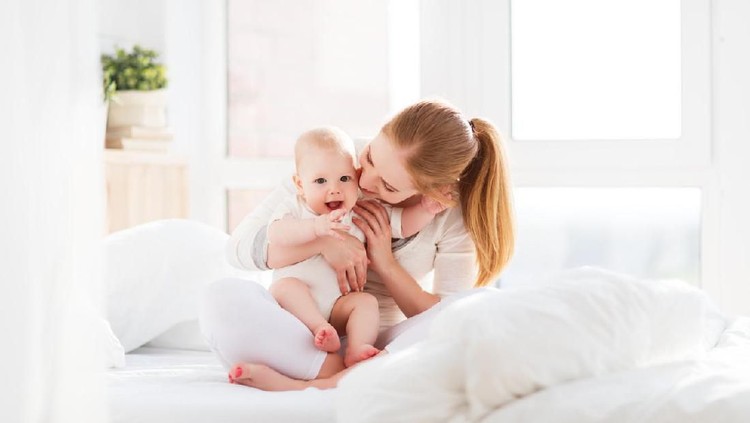 happy family mother playing and hug with newborn baby  in bed