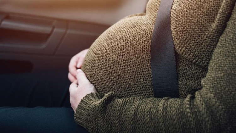 Pregnant woman with safety seat belt in the car