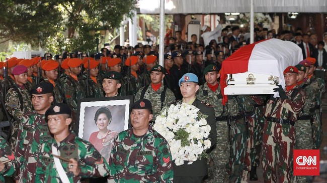 Empat perwira tinggi membentangkan bendera merah putih di atas liang lahat saat prosesi pemakaman Ani Yudhoyono.