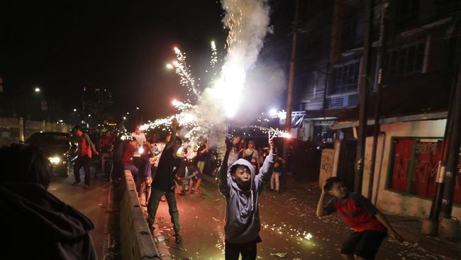 Indonesian youths light firecrackers and flares as they celebrate the end of the fasting month of Ramadan on a street in Jakarta, Indonesia, Tuesday, June 4, 2019. People in the world's most populous Muslim country flock to the streets in the capital on the eve of Eid al-Fitr which marks the end of the holiest month in Muslim calendar. (AP Photo/Dita Alangkara)
