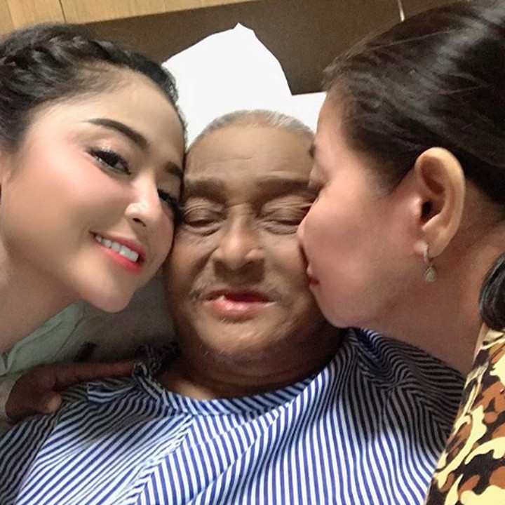 Bersama ibunda yang kebagian jadwal jaga ayahnya saat masih dirawat di rumah sakit. Sang ayah saat itu terlihat tersenyum meski terbaring lemah dan mengenakan baju khusus pasien. (Foto: Instagram @dewiperssikreal)
