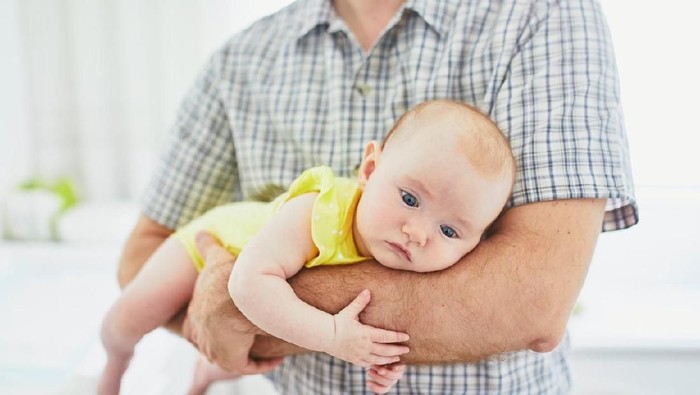 4 months adorable baby girl lying on tummy in her father's hands