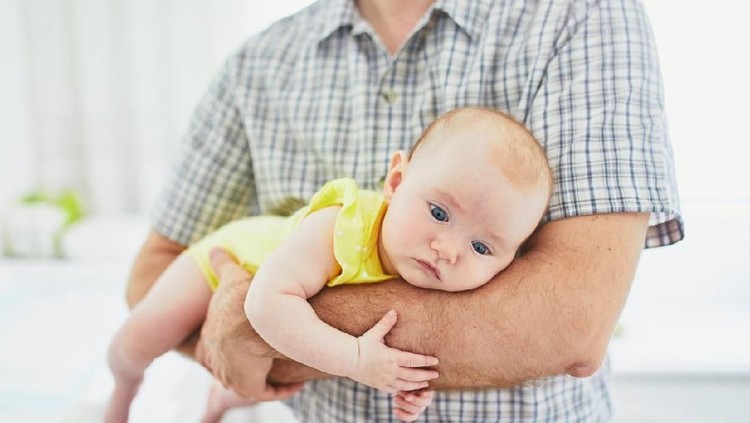 4 months adorable baby girl lying on tummy in her father's hands