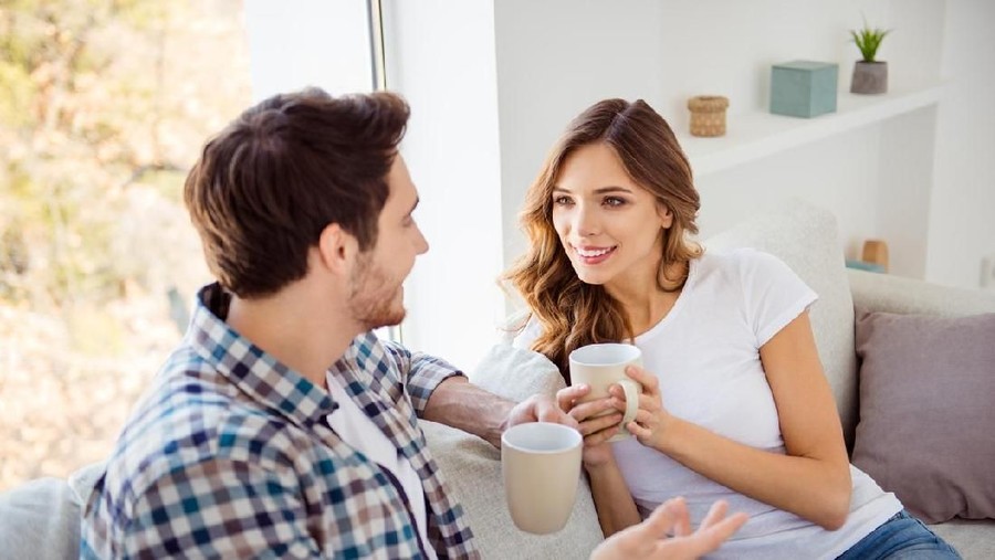 Nice-looking attractive lovely charming cute sweet cheerful guy lady sitting on couch sofa having fun time discussing news in light white style interior house indoors living room.