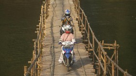 Warga menyeberangi sungai Progo melalui jembatan bambu di Desa Ngentakrejo, Lendah, Kulonprogo, DI Yogyakarta, Kamis (6/6/2019). Warga setempat memanfaatkan surutnya aliran Sungai Progo pada musim kemarau untuk membuat jembatan bambu sebagai jalur al