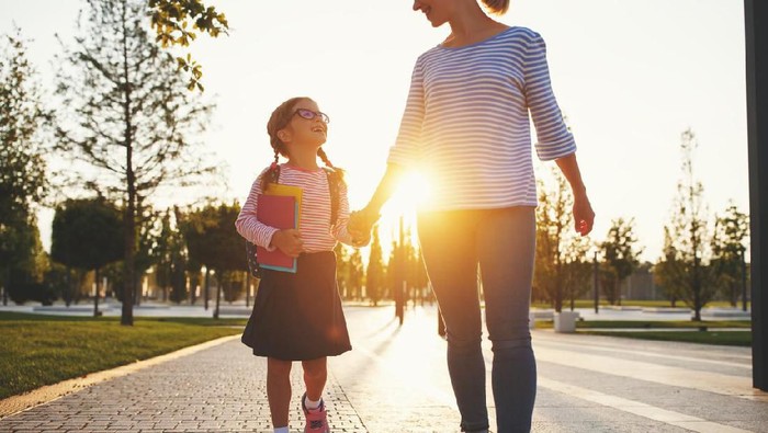 first day at school. mother leads a little child school girl in first grade