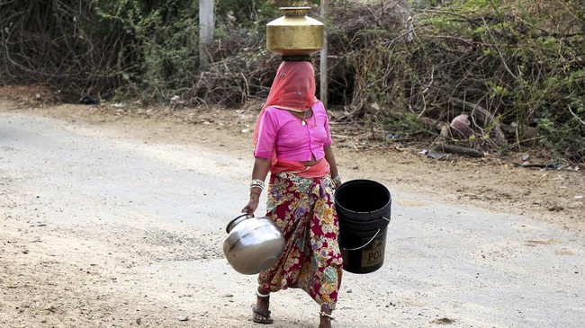 In this photo taken on on May 16, 2019, an Indian woman carries buckets and containers to collect drinking water from a road side water tap on the outskirts village of Ajmer, in the Indian state of Rajasthan. - Senior officials in the Public Health and Engineering Department (PHED) claimed on May 15 that the water crisis in the state of Rajasthan does not warrant a situation of running water trains and the priority now is to supply drinking water by tankers, local reports said. (Photo by Himanshu SHARMA / AFP)