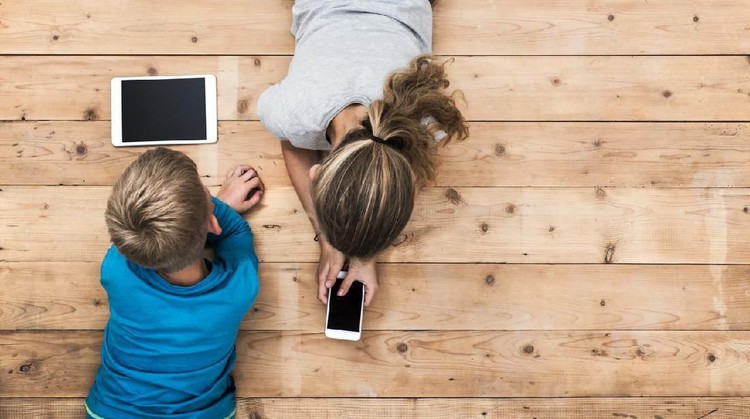 Top view image of two kids lying on the floor and playing with tablet and smartphone watching movie or gaming. Mockup or template for web or application design.