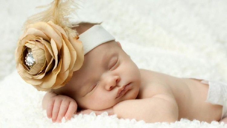nama bayi Sleeping newborn baby girl with vintage gold headband.