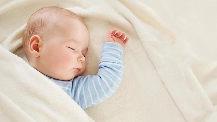 Close-up of sleeping baby hand in the mother's hand on the bed. New family and baby sleep concept