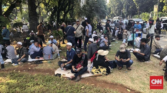 Sejumlah peserta demo sengketa Pilpres 2019 di Patung Kuda terlihat duduk dan makan di tikar yang digelar di atas rumput.
