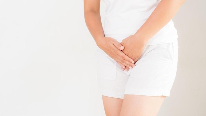 Young woman in yellow short dress standing with her hands between legs, needs a restroom, isolated for white background. Women's health, gynecology.