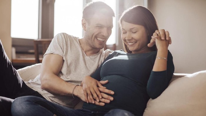 Husband touching wife's stomach, trying to feel baby.