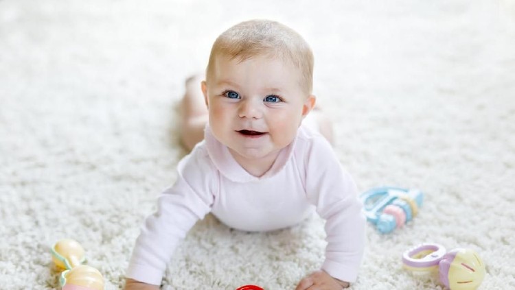 Cute baby playing with colorful pastel vintage rattle toy. New born child, little girl looking at the camera and crawling. Family, new life, childhood, beginning concept. Baby learning grab