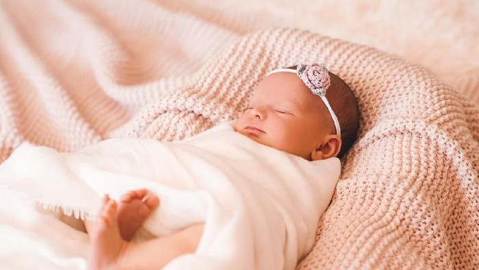 Cute smiling baby girl sleeping in cot closeup. Childhood.