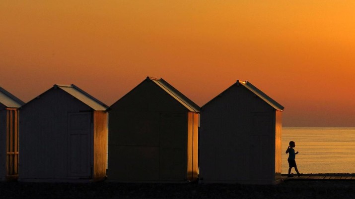 A child walks beside beach cabins on a pebbled beach, during sunset as a heatwave hits France, in Cayeux-sur-Mer, France, June 29, 2022. REUTERS/Pascal Rossignol     TPX IMAGES OF THE DAY