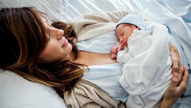 Mother holding her newborn baby in hospital bed