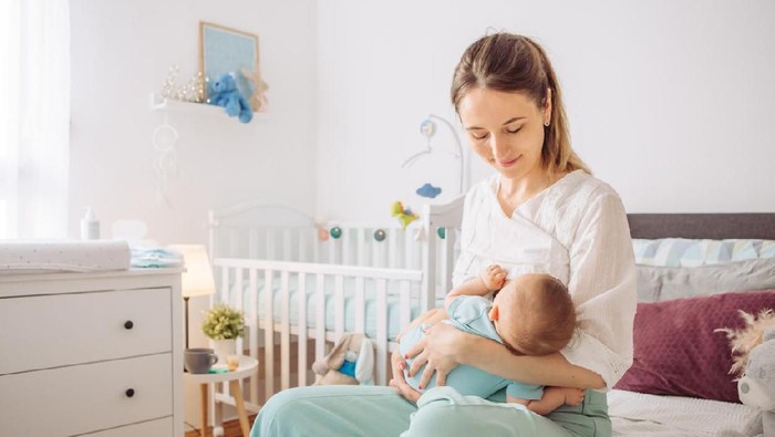 Mother breastfeeding baby son in bedroom, they enjoy in this moment together