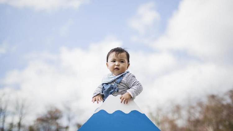 Asian baby boy climbing a miniature model of Mt.Fuji.